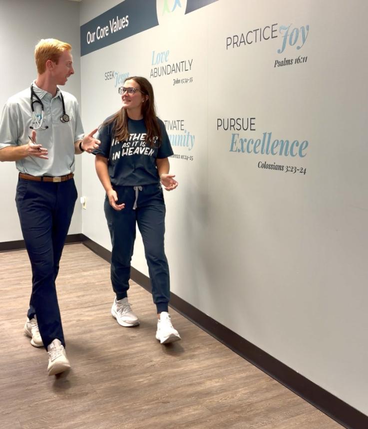 photo of Dr. Cole Phillips walking downa hall in conversation with a woman.